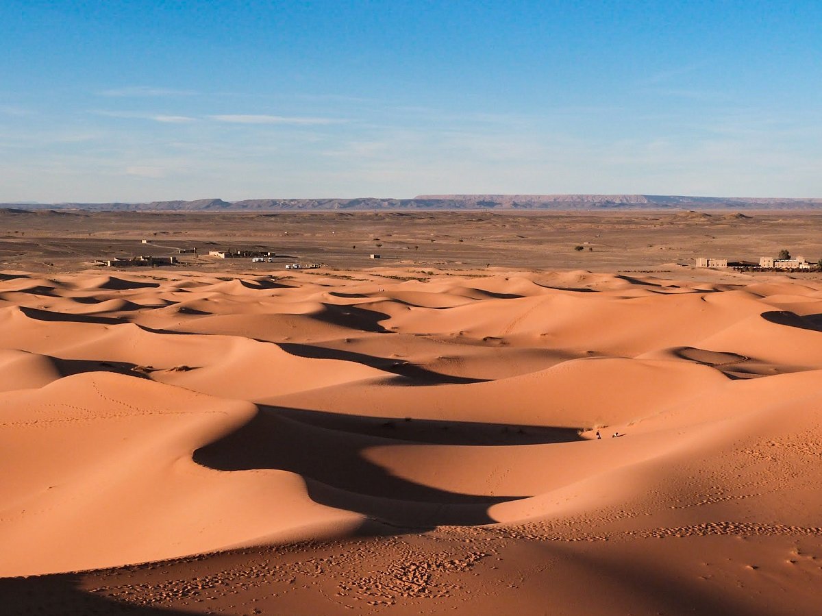 Traveller walking along the crest of a dune in Merzouga